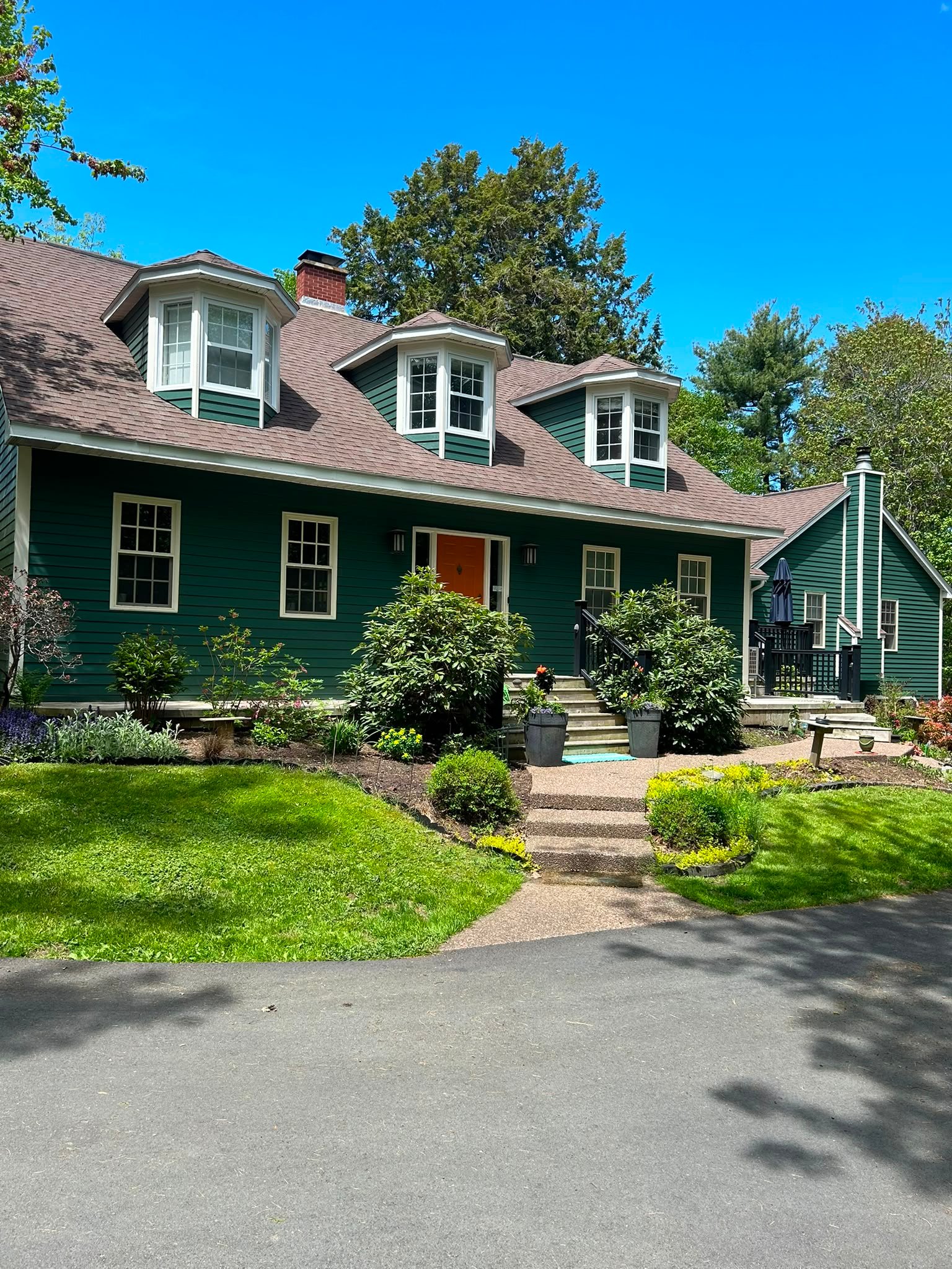 Forest green Cape Cod home with white trim and orange front door